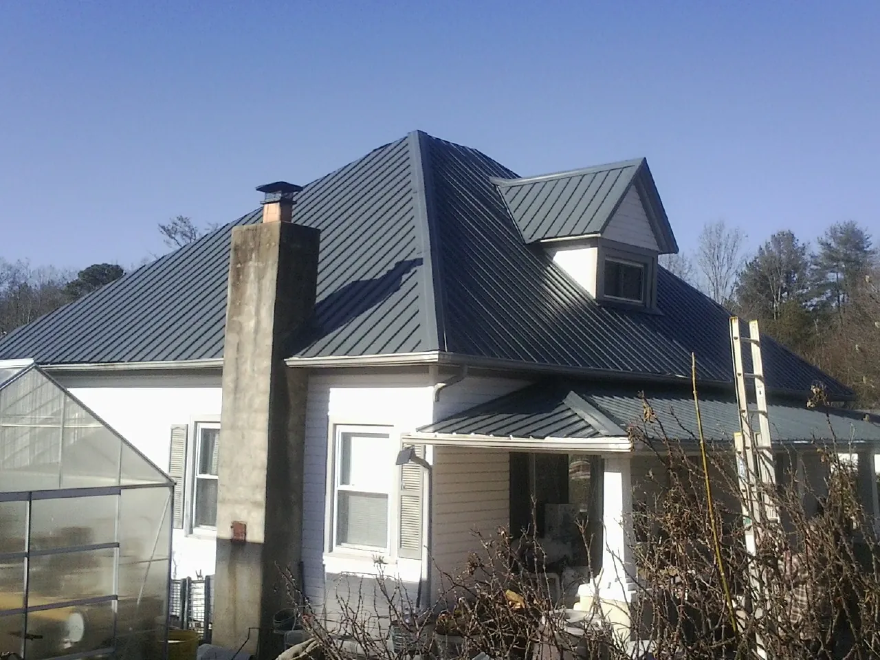 Dark blue standing seam metal roof on a white farmhouse with dormer — Slate & Tile Roof Repair by Roofing Brothers in Grand Saline