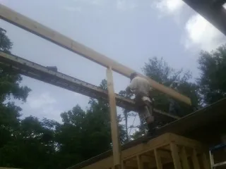 Carpenter setting a ridge beam over a new addition frame — Ice Dam Removal by Roofing Brothers in Grand Saline
