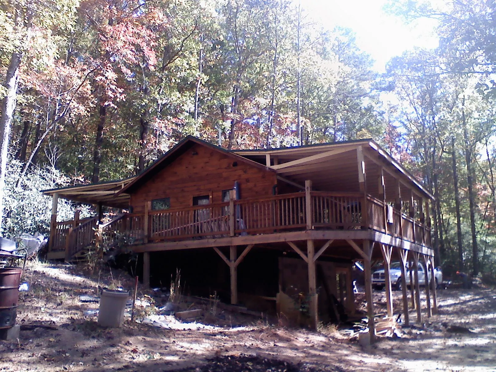 Log cabin with a wraparound porch and metal roof in the fall in Grand Saline