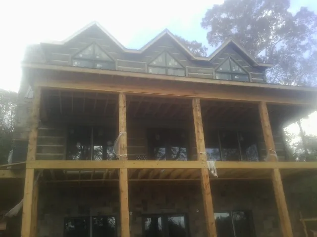Dormers and porch framing on a large log home under construction — Roof Coating work by our crew in Grand Saline