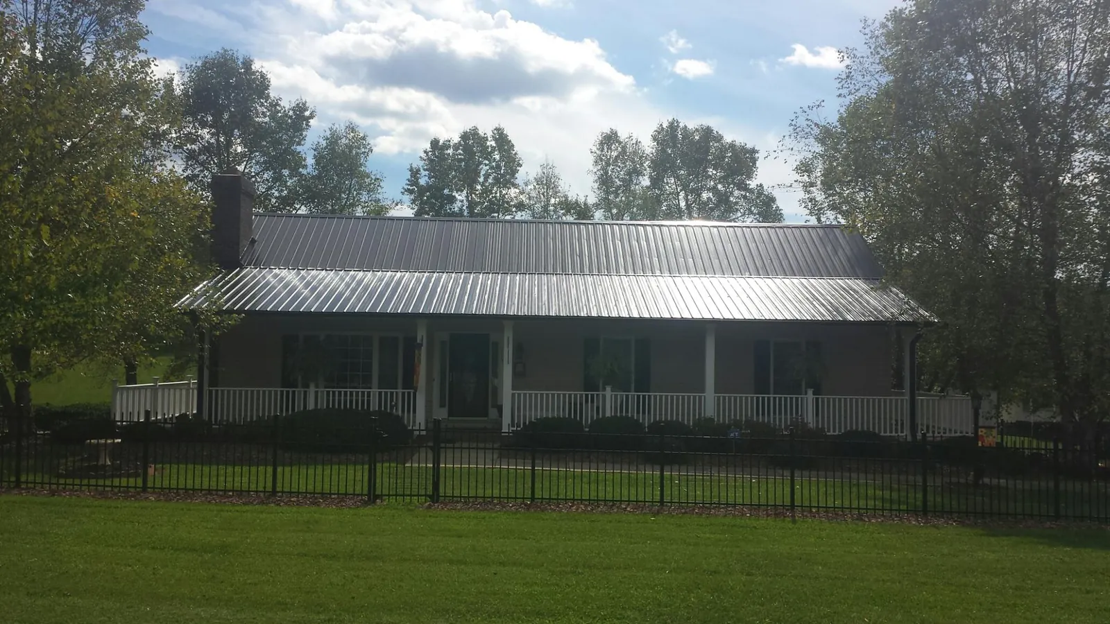 Gray metal roof on a brick ranch with a full width front porch — Gutter Guard Installation work by our crew in Grand Saline
