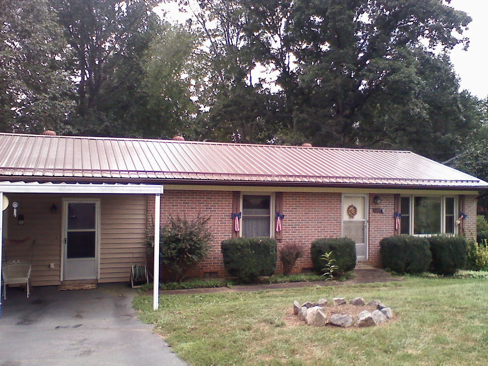 Bronze metal roof and carport on a brick ranch home — Roof Repair work by our crew in Grand Saline
