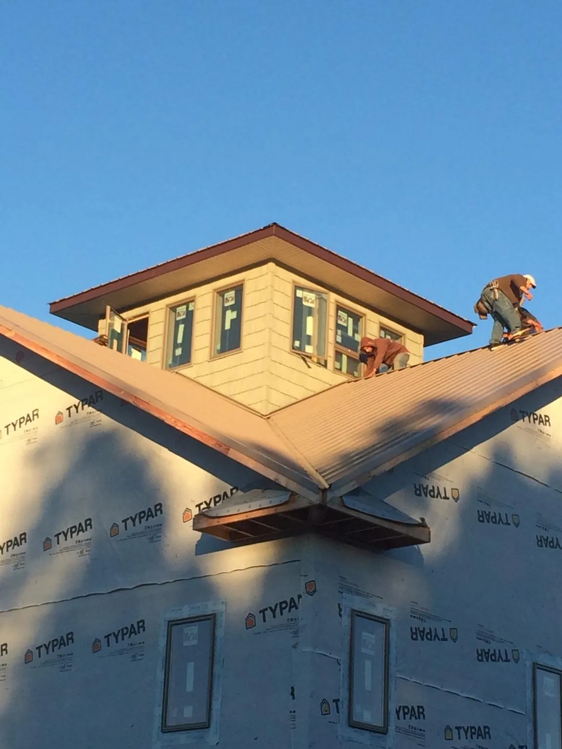 Roofers working around a rooftop cupola on a new metal roof at sunset — Roof Waterproofing in Grand Saline by Roofing Brothers